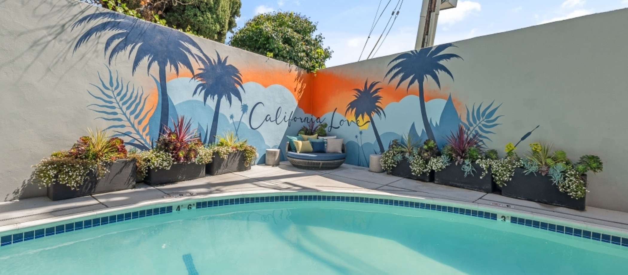 A pool surrounded by palm trees and a colorful mural at 2727 Edison in San Mateo, California.