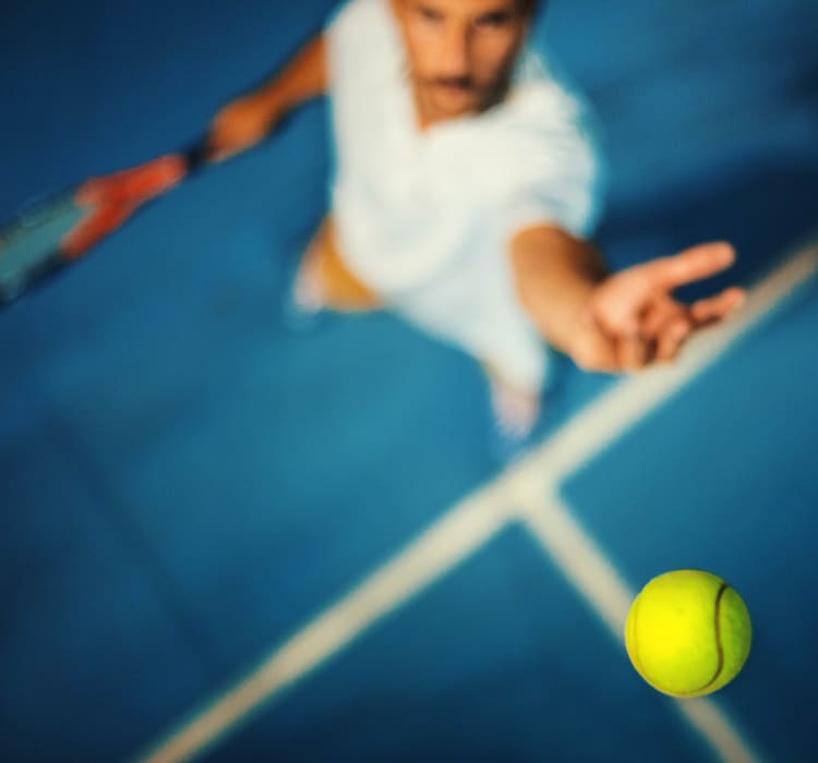 Resident mid-serve on the tennis courts at Clear Lake Place in Houston, Texas