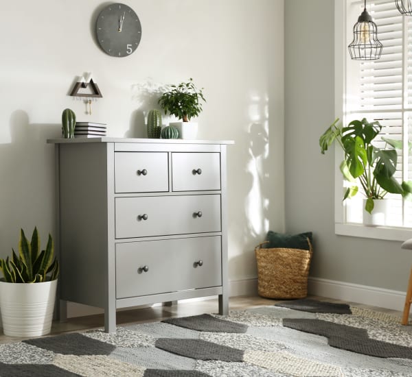 A bright apartment bedroom with a dresser and potted plants at Lullwater at Blair Stone in Tallahassee, Florida Lullwater at Blair Stone in Tallahassee, Florida