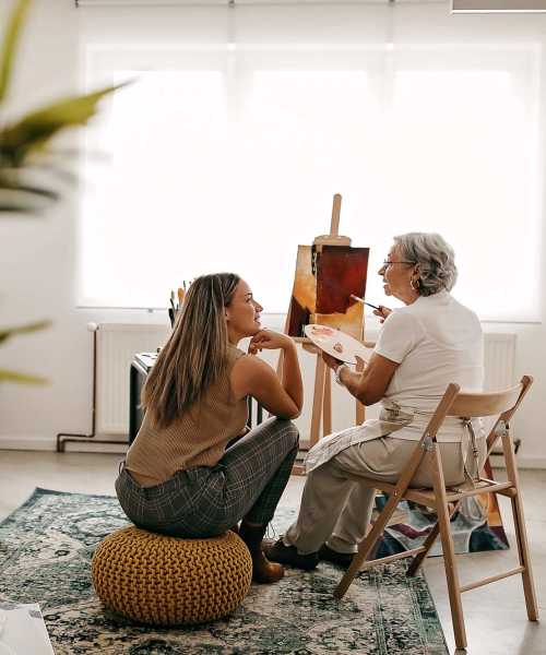 Woman teaching painting to her daughter in her living room at Athens Vista Senior Apartments in Los Angeles, California