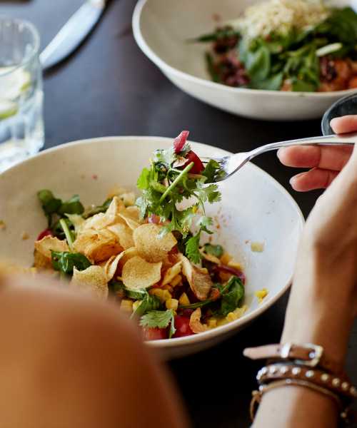 Woman eating a salad at a restaurant near Towns At Eastland in Charlotte, North Carolina