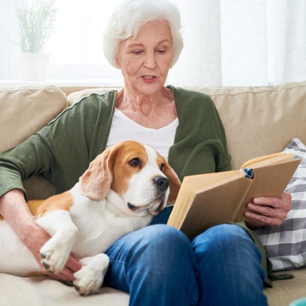 Woman with dog reading a book at Pacifica Senior Living Sterling in Sterling, Virginia
