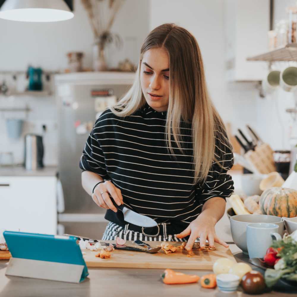 Woman cutting vegetables in kitchen at Coral Wood Court in Reseda, California
