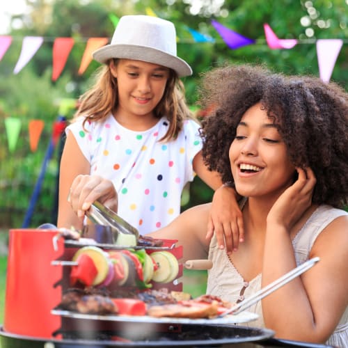 A mother with her daughter grilling meat at The Village at NTC in San Diego, California