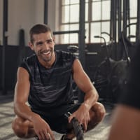 A man smiling while grabbing a rope in the fitness center at Ravella at Town Center in Jacksonville, Florida