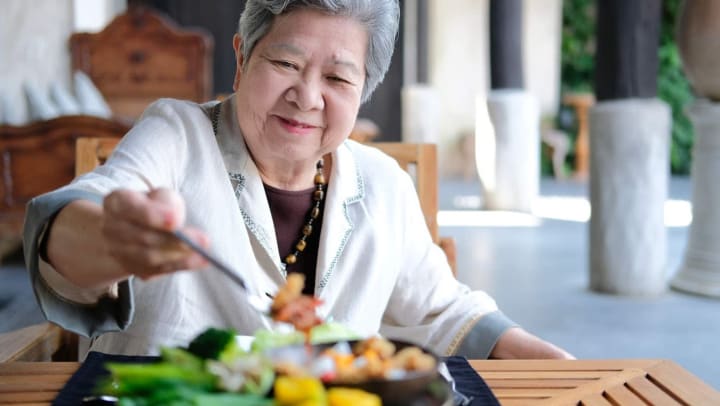 Senior woman reaching for food with fork