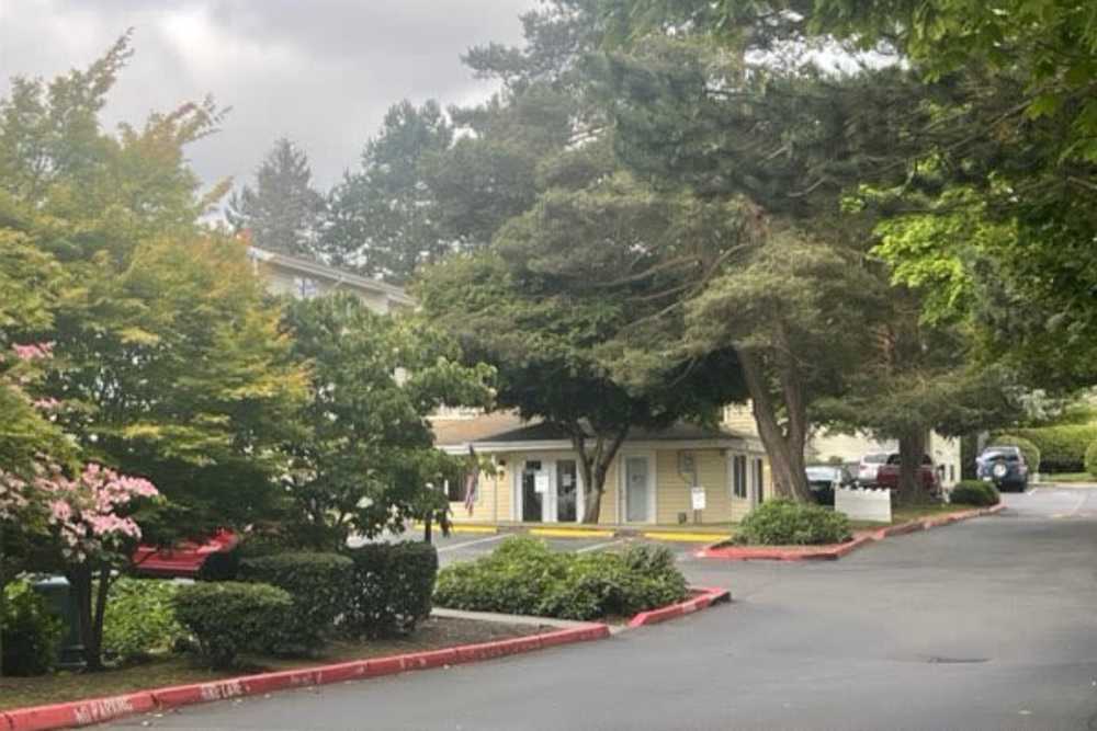 Front entrance with parking lot at Amber Glen Apartments in Everett, Washington