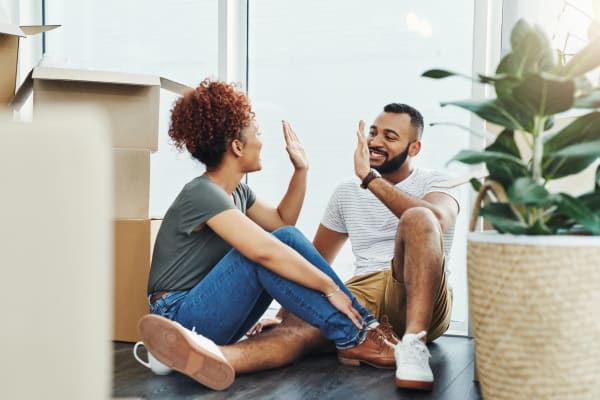 Couple high fiving on the floor after getting all moved into their new place at Reserve at South Creek in Englewood, Colorado