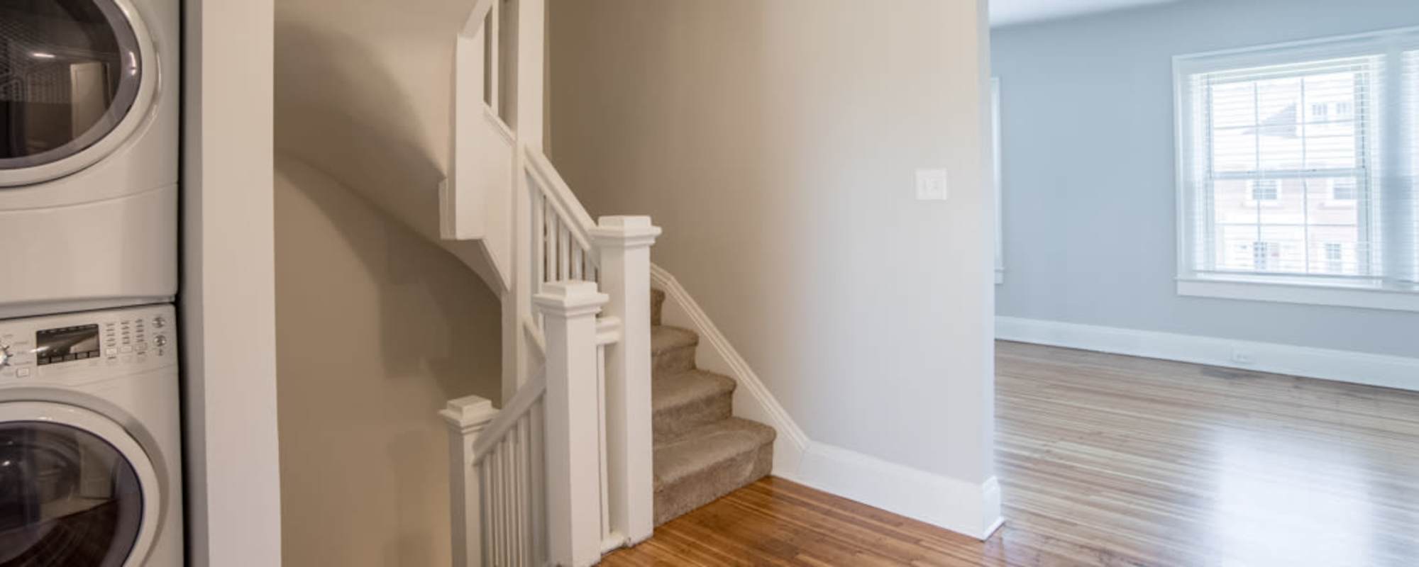 Stacked washer and dryer in living space with wood floors at  Buckingham and Balmoral in Indianapolis, Indiana