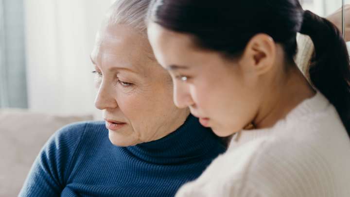 Two women sitting on a couch close to each other
