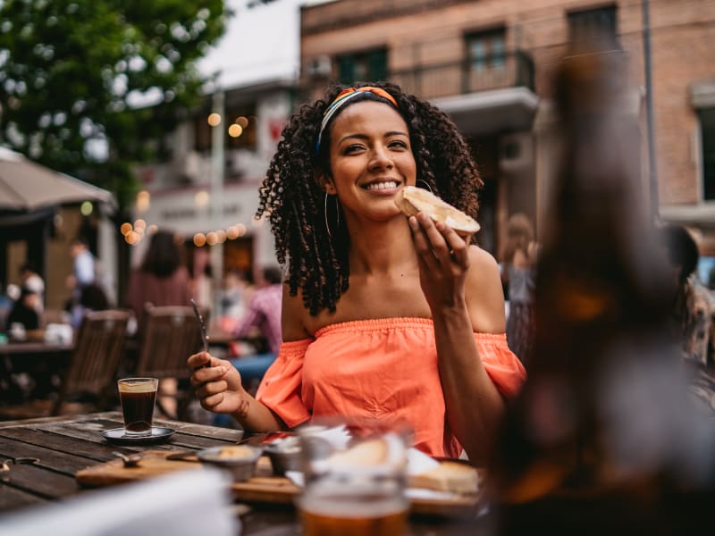 A woman eating outside of a restaurant near Springwoods at Lake Ridge in Woodbridge, Virginia