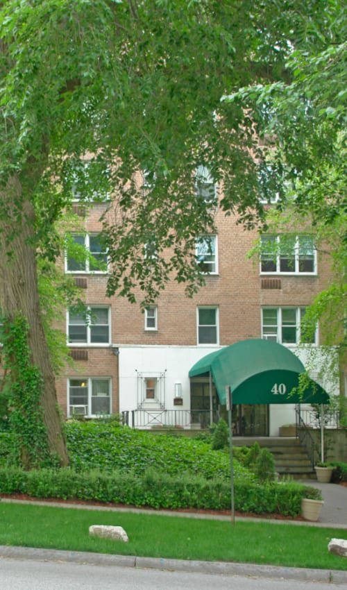 Exterior photo of the building surrounded by lots of pretty trees and green grass at Eastgold Westchester in Dobbs Ferry, New York