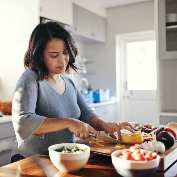 Resident woman chopping vegetables in an apartment kitchen at 21 Kristin Apartments in Schaumburg, Illinois