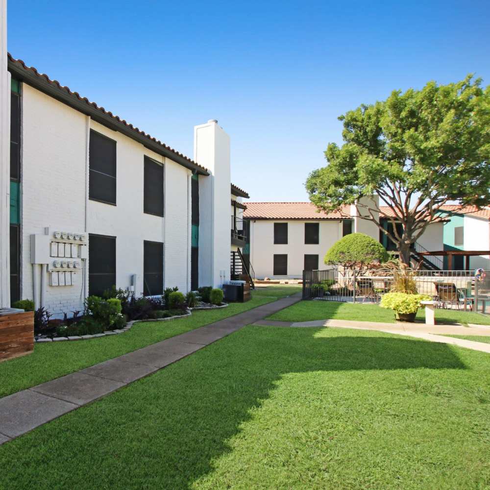 Apartment community courtyard with a landscaped lawn at Athena Apartments in Benbrook, Texas