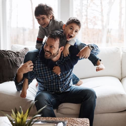 A resident playing with his kids on the couch at Albany Hill Village in Albany, Georgia