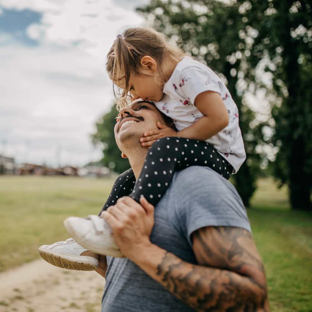 Father carrying her daughter on his shoulders near The Anderson at Brooks in San Antonio, Texas
