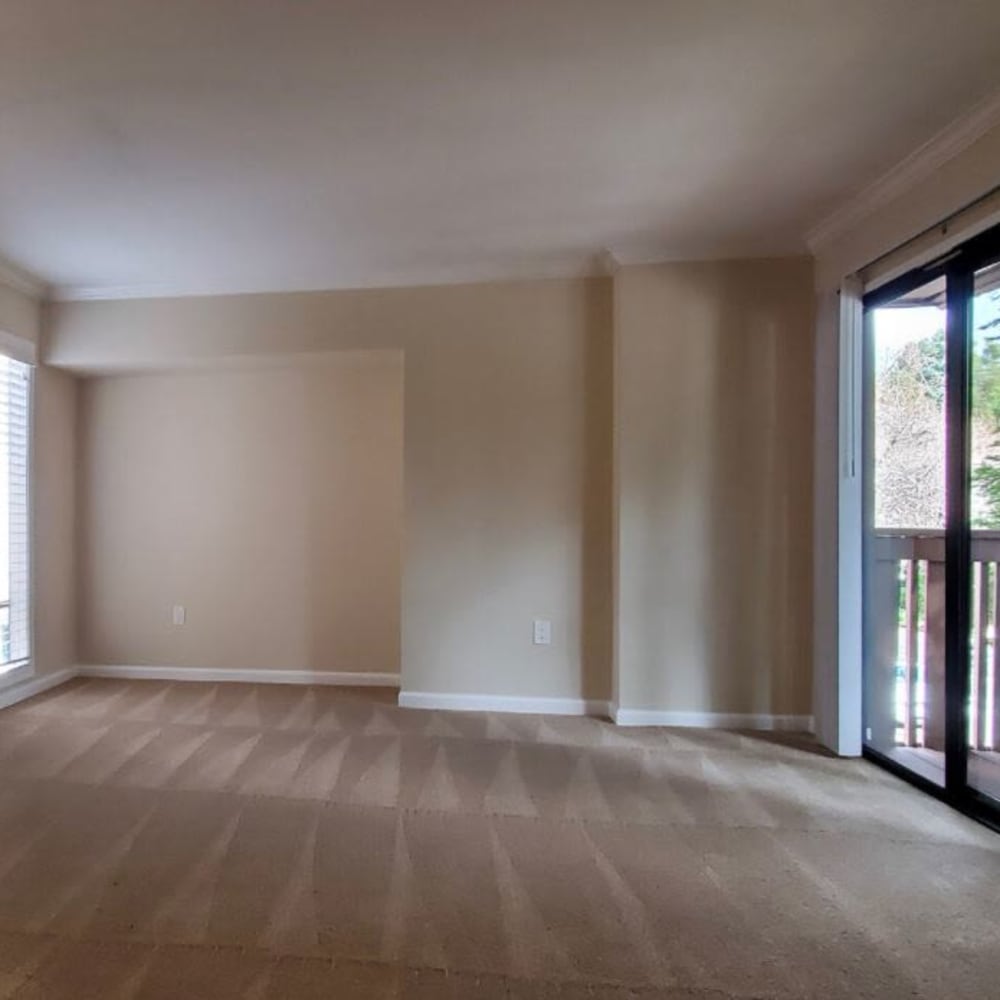 Spacious carpeted living room with private balcony access at Mission Rock at Marin in San Rafael, California