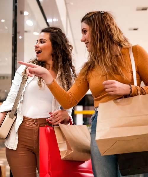 Two women browsing through clothing racks in a store at Edge DTC in Denver, Colorado