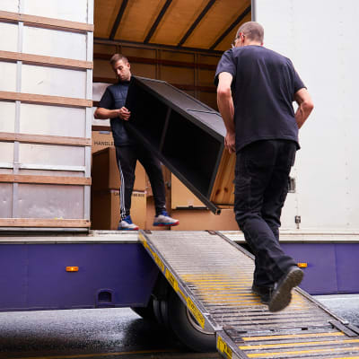Two men loading furniture into a moving truck near A-American Self Storage in Dacono, Colorado