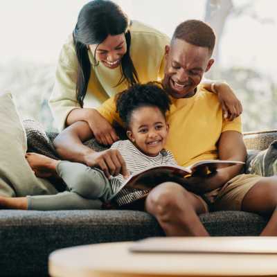 A happy family reading a book on the couch at The Enclave at Bear Creek in Euless, Texas