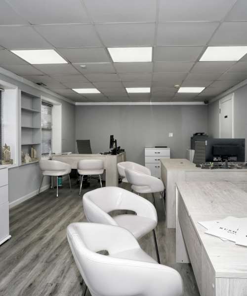 Modern leasing office with white desks, stylish chairs, and wood-style flooring at Dutch Village Apartments in Baltimore, Maryland