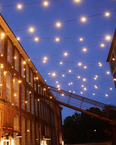 Twinkle lights hanging between two brick buildings near Revolution Mill in Greensboro, North Carolina