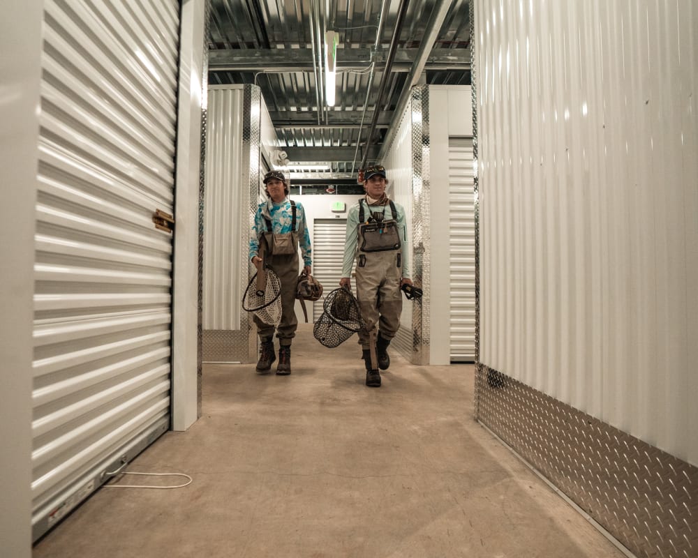 Two customers in waders return to their storage unit after a fishing trip.