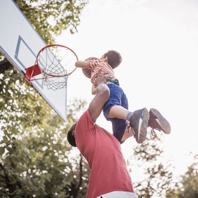 A father holding his kids at basketball courts near Chollas Heights Historical in San Diego, California