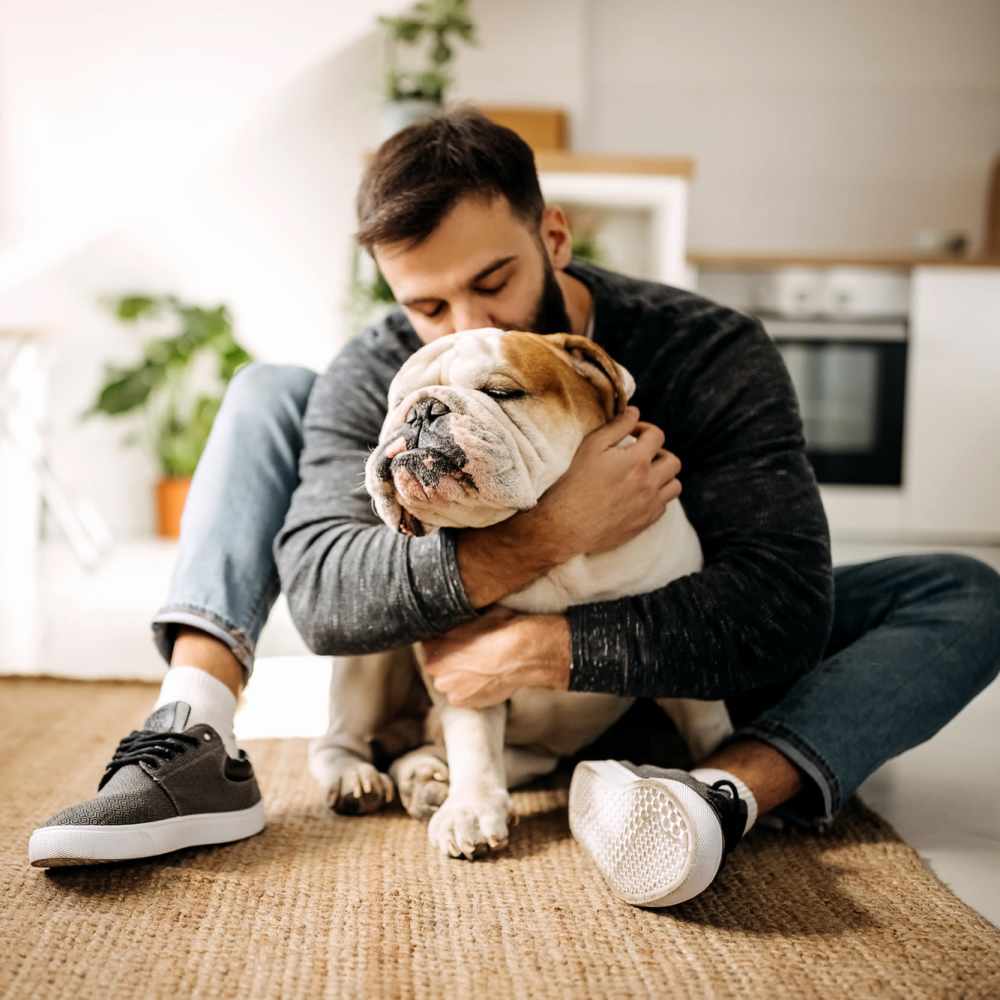 Living room with man cuddling bulldog at Russ Town Crossing in Ruston, Louisiana