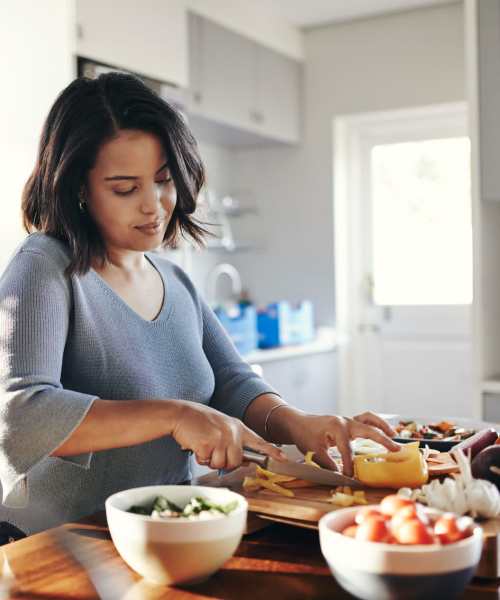 Resident woman chopping vegetables in her apartment kitchen at District at 54 in Raleigh, North Carolina