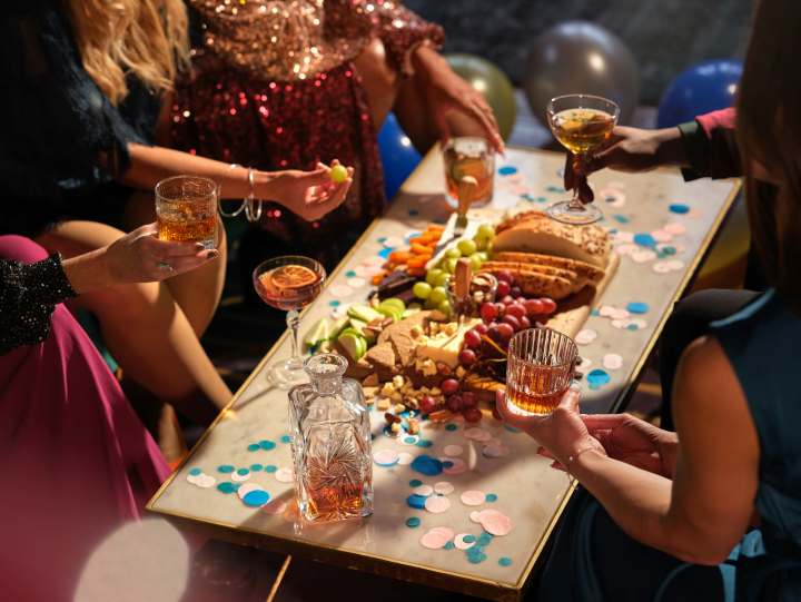 a group of people surround a small table with a charcuterie board and drinks