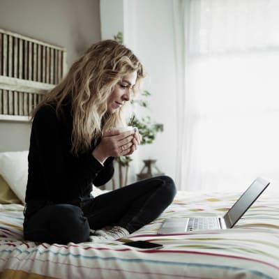 A resident working on her laptop in a bedroom at Discovery Village in Joint Base Lewis McChord, Washington