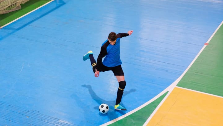 soccer goalie winds up to kick the soccer ball in an indoor soccer gym | indoor soccer league around Phoenix