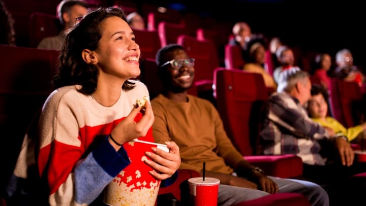 two friends watching a movie and eating popcorn | movie theaters in Charlotte
