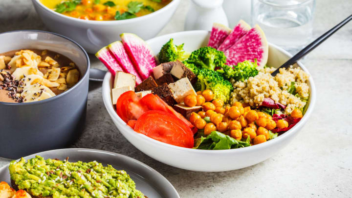 a buddha bowl with chickpeas, quinoa, and various vegetables served with soup and other dishes on a table | restaurants in Carrollton