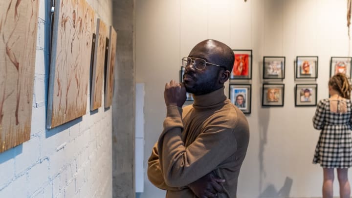 A man admiring art on the wall at a gallery in Keller.