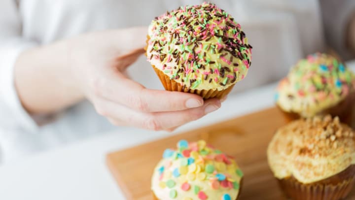 A close up of a woman holding a cupcake from a local bakery | bakeries near Brunswick