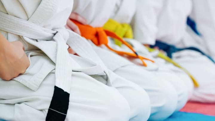 Close up of people’s torsos wearing martial arts outfits with different colored belts | Martial Arts Studios in Savannah