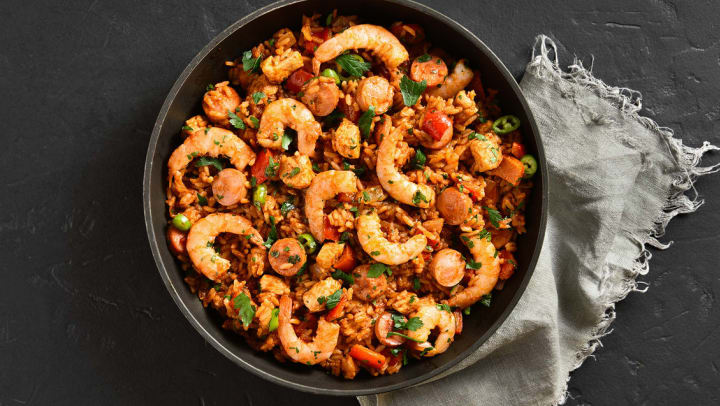 The top view of a large bowl of jambalaya with chicken, smoked sausages and vegetables sitting on a black stone table in a Keller restaurant.