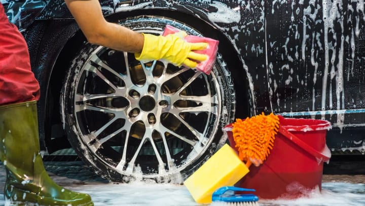 man scrubbing tire rims of a car with pink sponge | auto detailing in Irving