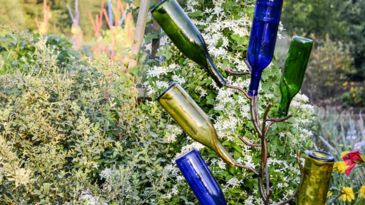 A sculpture of colorful glass bottles on display at an outdoor park | public art in Frisco