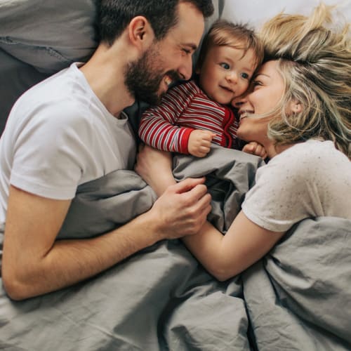 Residents snuggling their small child in a bed at Lovell Cove in Patuxent River, Maryland