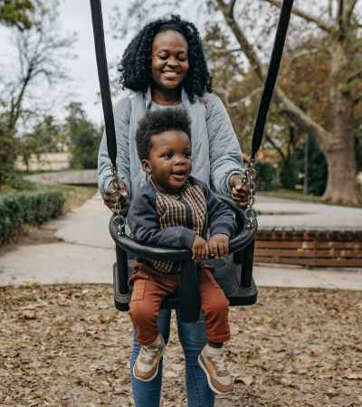 Woman pushing toddler on swing near The Baxter at Westwood in Austin, Texas
