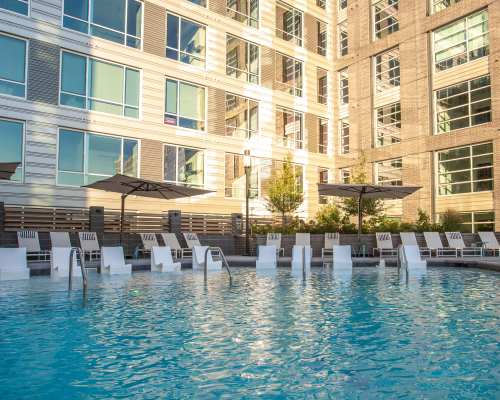 Resort-style swimming pool with sun loungers by the pool at Highland North Hills in Raleigh, North Carolina