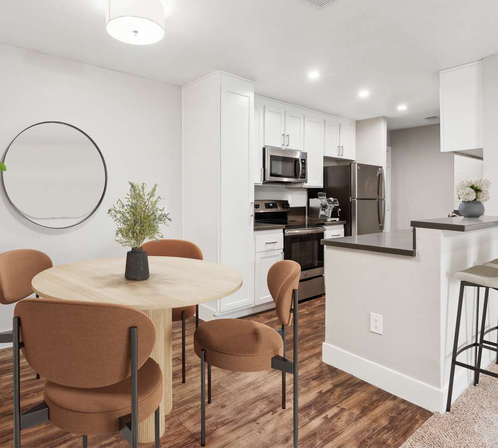 Kitchen with white cabinets, quartz counters, and stainless steel appliances, and dining area at Muirwood Apartment Homes in Martinez, California