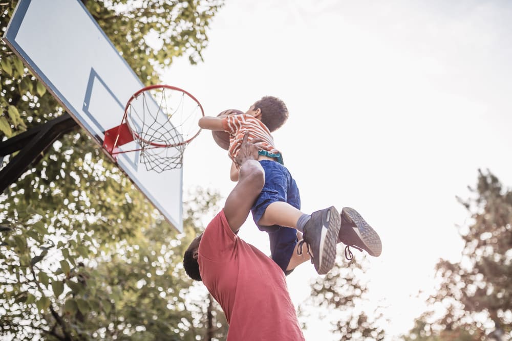 Man playing basketball with son at Cornfield Apartments in Ellington, Connecticut