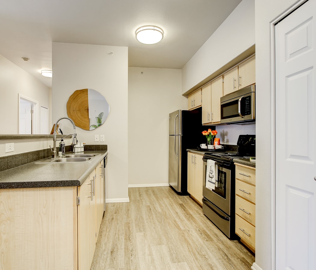 Modern kitchen with pantry and stainless-steel appliances in a model home at River Trail Apartments in Puyallup, Washington