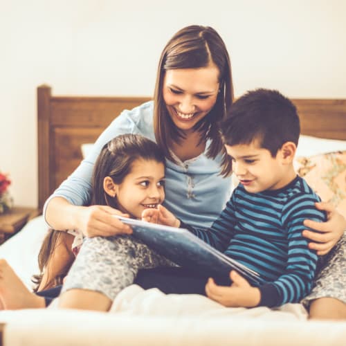 A resident reading to two kids in a bedroom at Lovell Cove in Patuxent River, Maryland