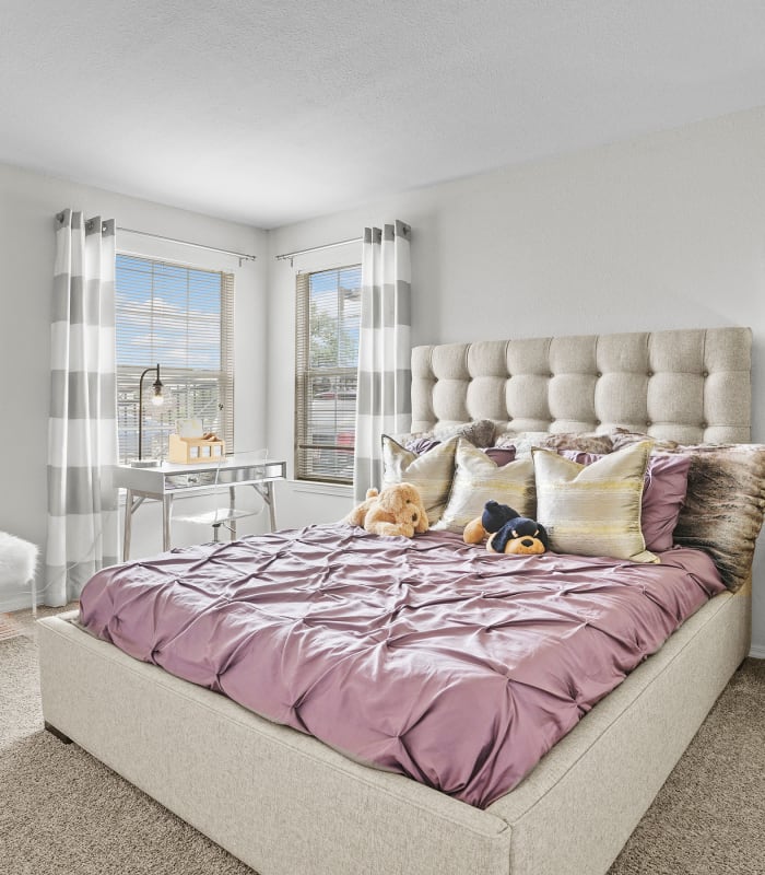 Spacious carpeted bedroom with pink bed at The Remington Apartments in Wichita, Kansas