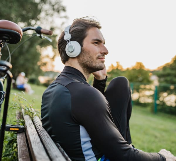 A man sitting on a park bench with headphones on near Retreat at Fairhope Village in Fairhope, Alabama